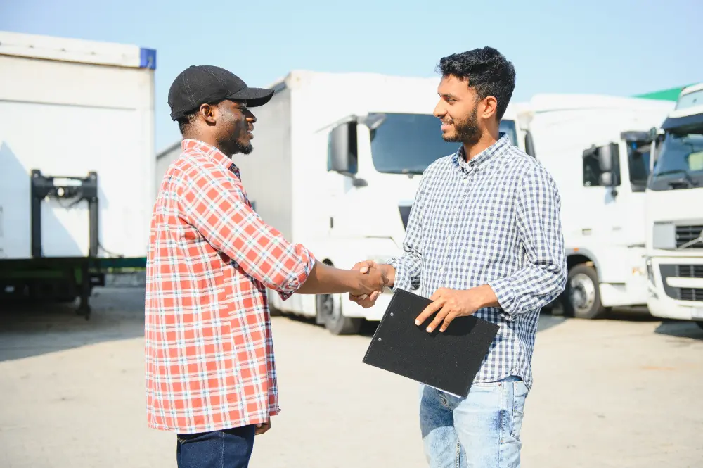 two people shaking hands near a truck